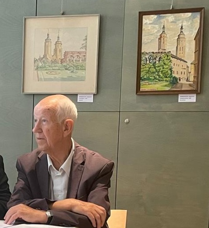 Diether Ertel bei der Jahreshauptversammlung 2025 vor einer Wechselausstellung von Jägerndorfer Stadtansichten